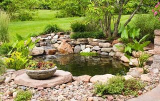 Tranquil garden pond with waterfall and lush greenery.