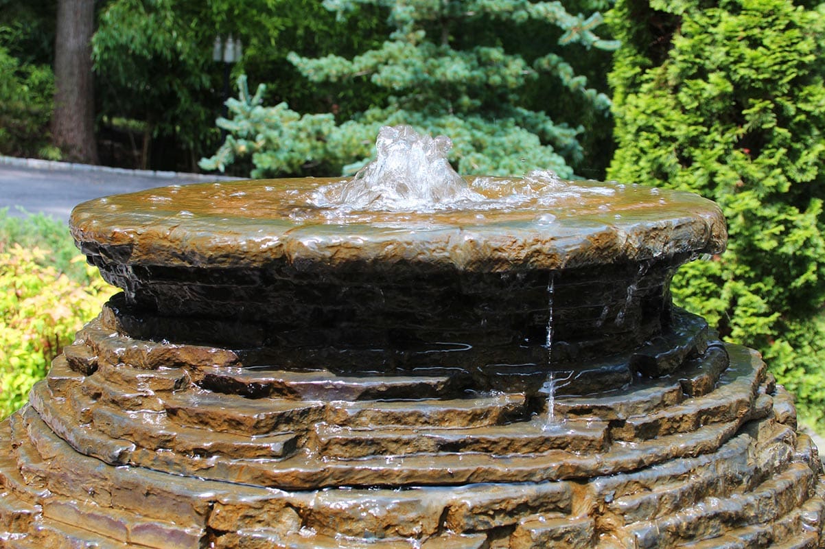 Water cascading down tiered outdoor garden fountain.